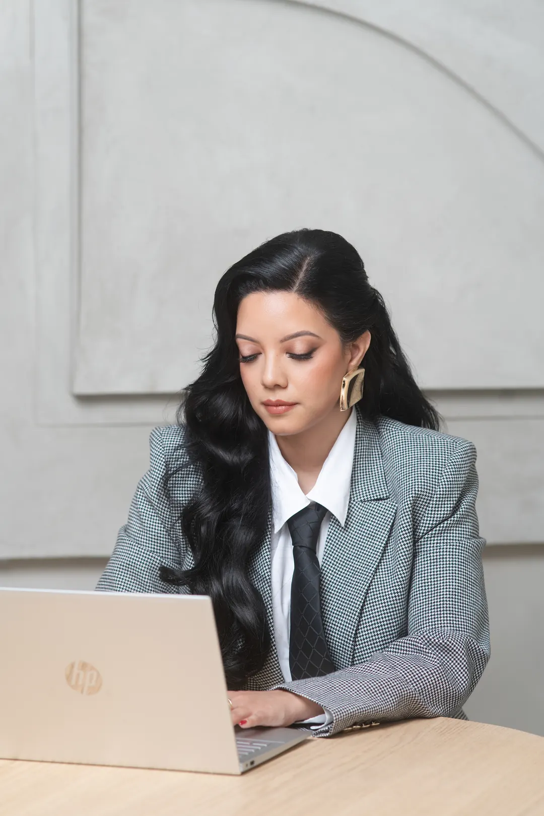 Priscilla Laclé working at a laptop in a checked blazer