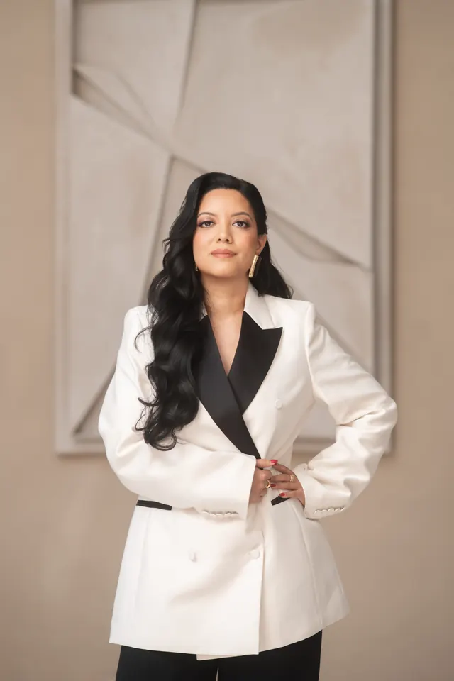 Priscilla Laclé in a white suit with one hand on her hip