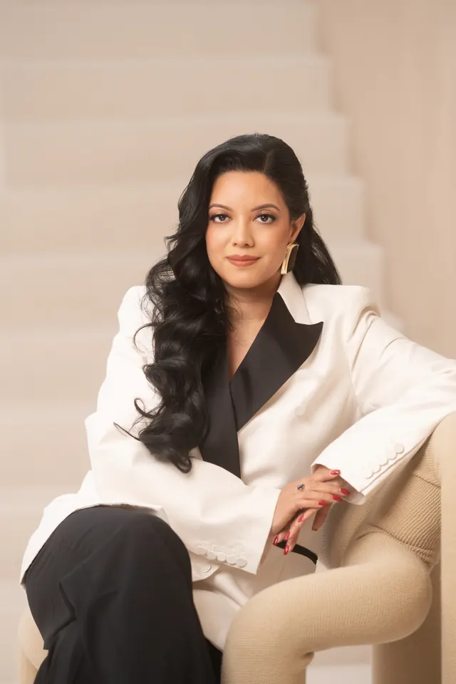Priscilla Laclé seated on a cream sofa in a white suit